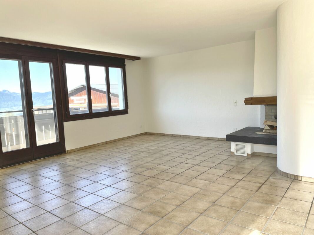 Heller leerer Wohnraum mit Fliesenboden und Kamin