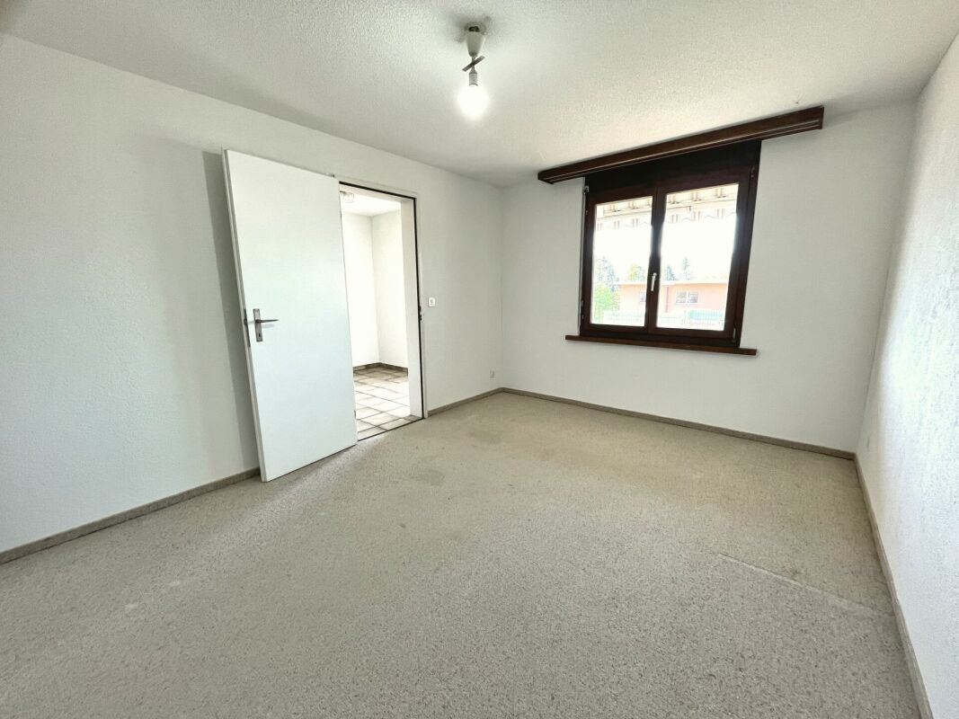 Leeres, schlichtes Zimmer mit Fenster und offener Tür