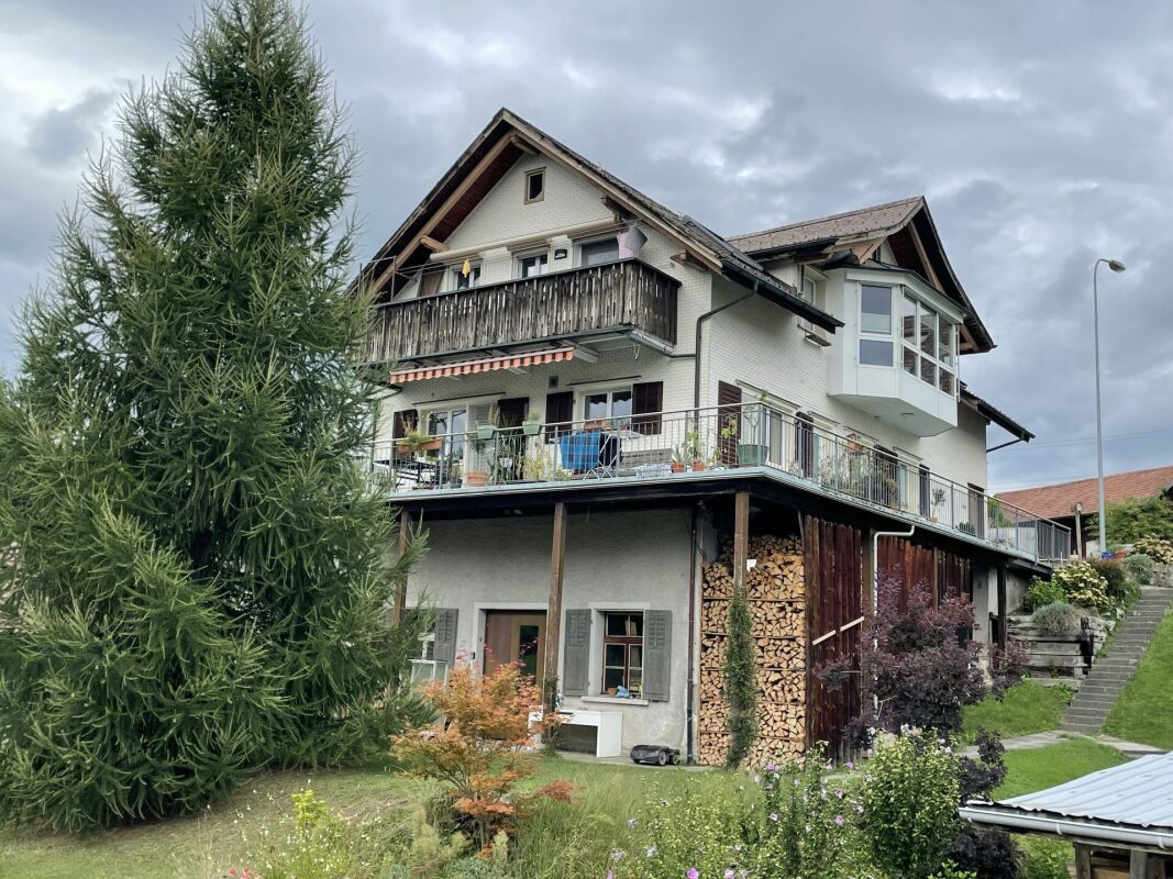 Außenansicht eines mehrgeschossigen Wohnhauses mit Balkon und Garten
