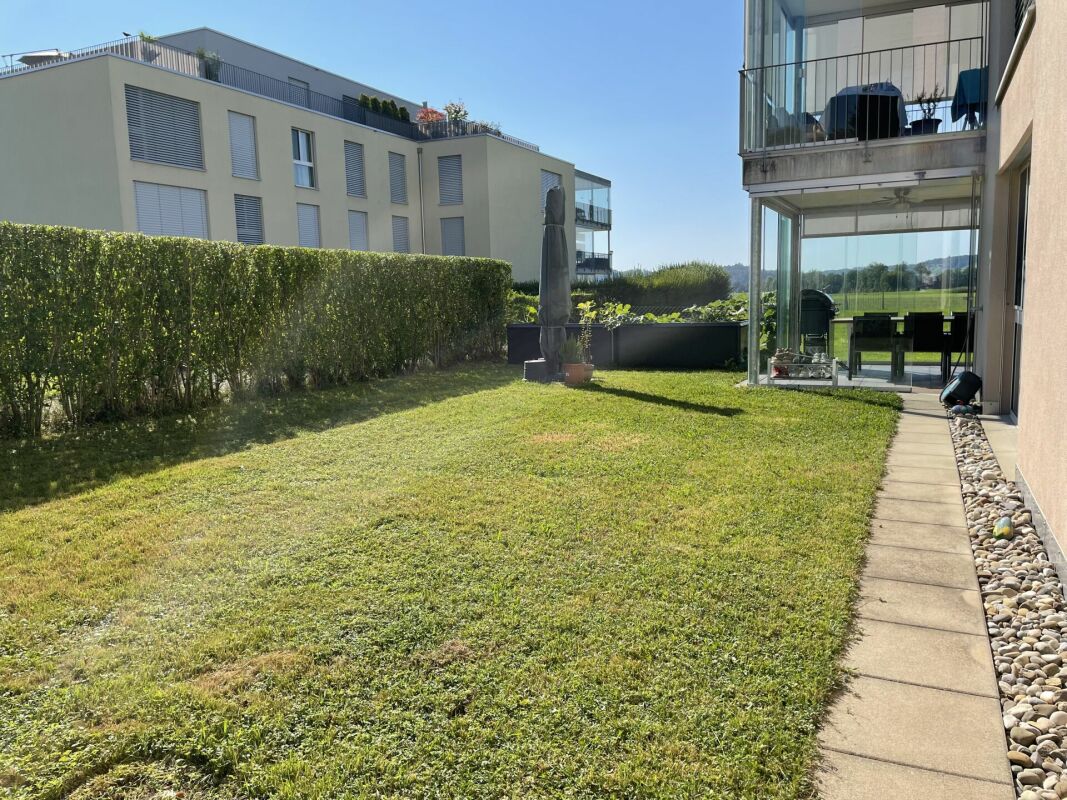 Garten mit Terrasse und moderner Wohnanlage