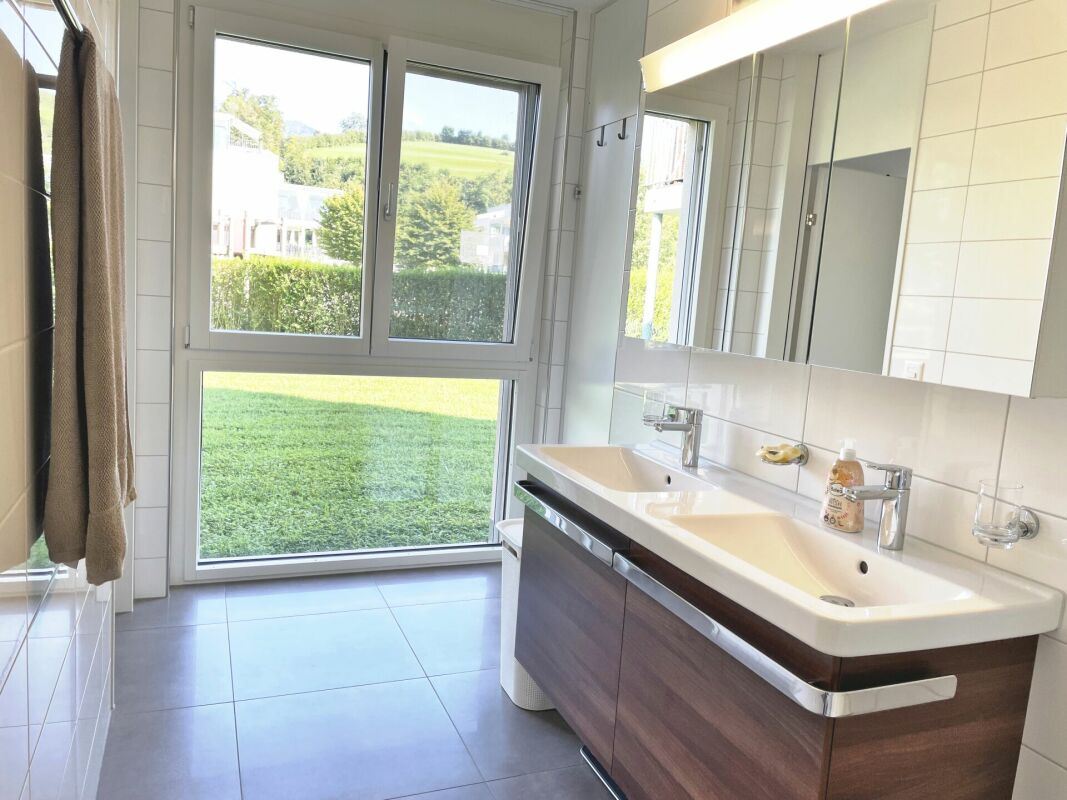 Helles Badezimmer mit Doppelwaschtisch und Gartenblick