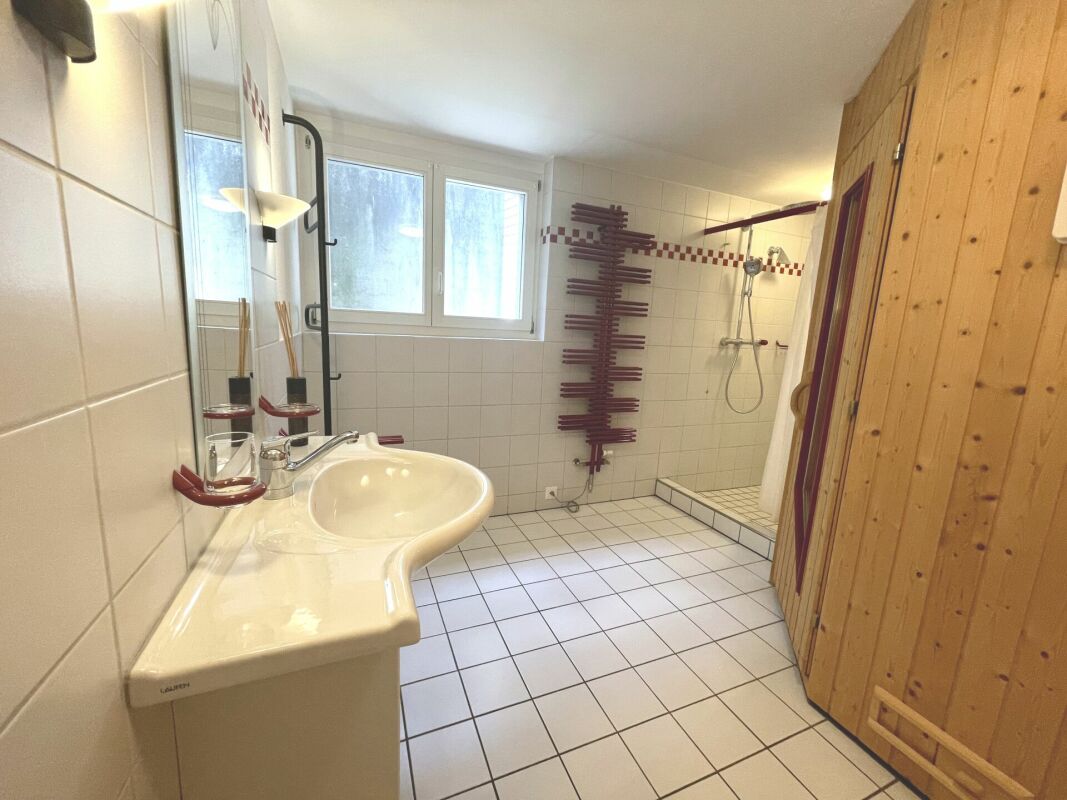 Helles Badezimmer mit Dusche und Holzschrank