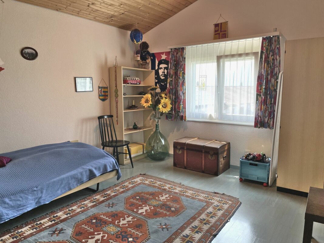 Bunt eingerichtetes Schlafzimmer mit Holzdecke