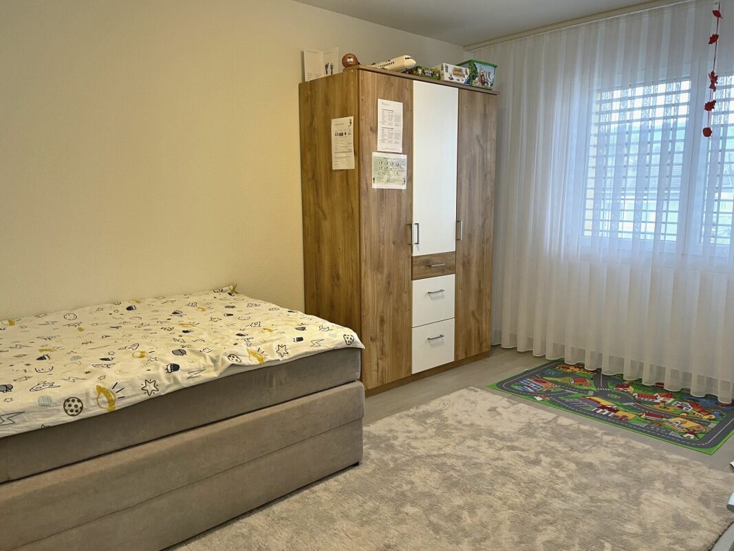Kinderzimmer mit Bett, Kleiderschrank und Fenster