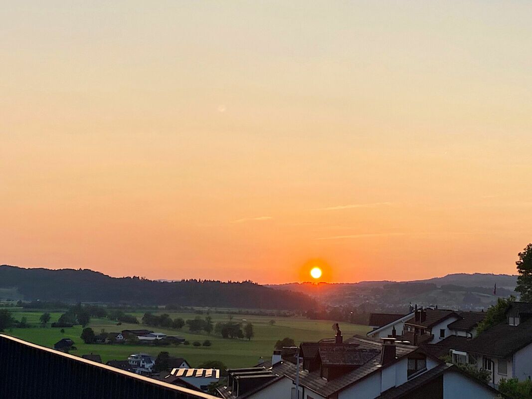 Sonnenuntergang über Tal und Wohnhäusern