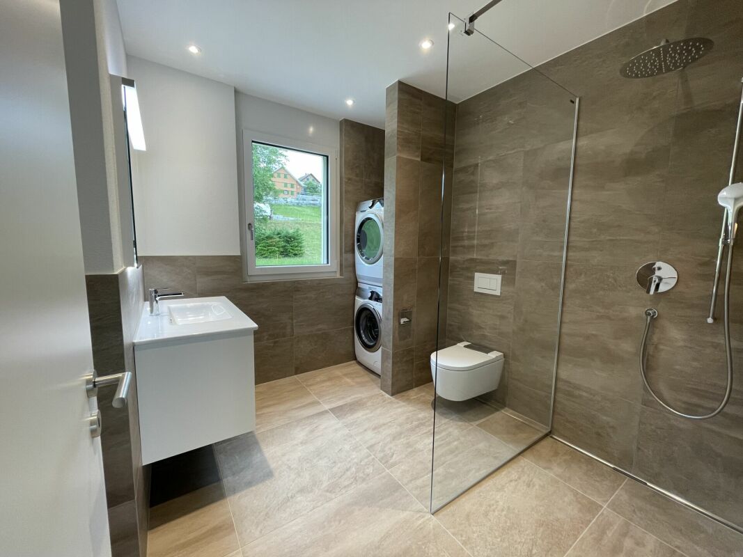 Modernes Bad mit Dusche, Waschtisch und Waschmaschine