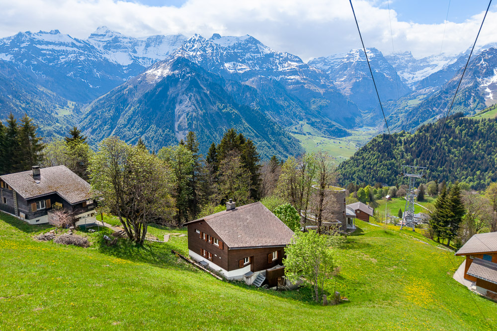 Alpine Hanggemeinde mit Holzhäusern und Panoramabergblick