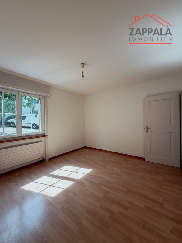 Leeres helles Zimmer mit Fenster und Holzboden