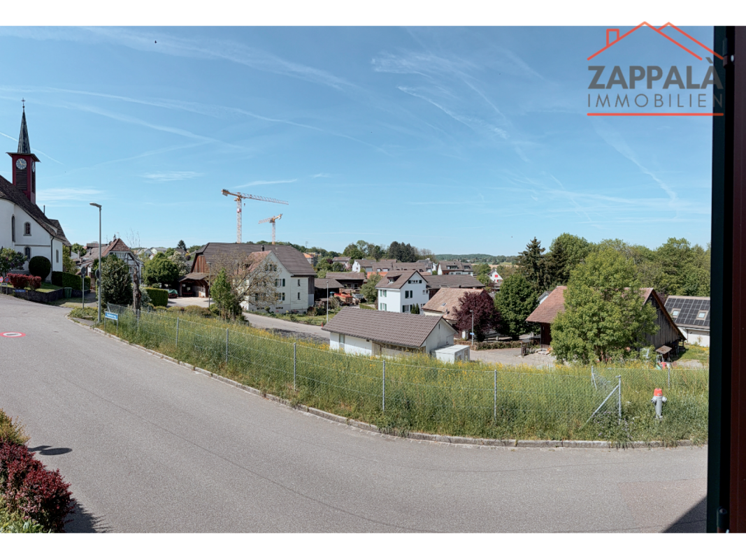 Blick über ein Wohngebiet mit Kirche und Himmel