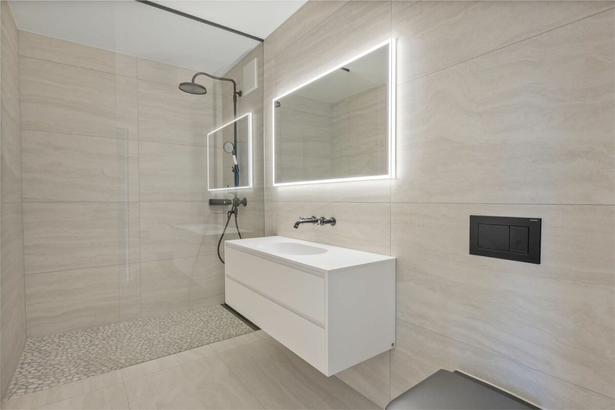 Modernes Badezimmer mit begehbarer Dusche und beleuchtetem Spiegel