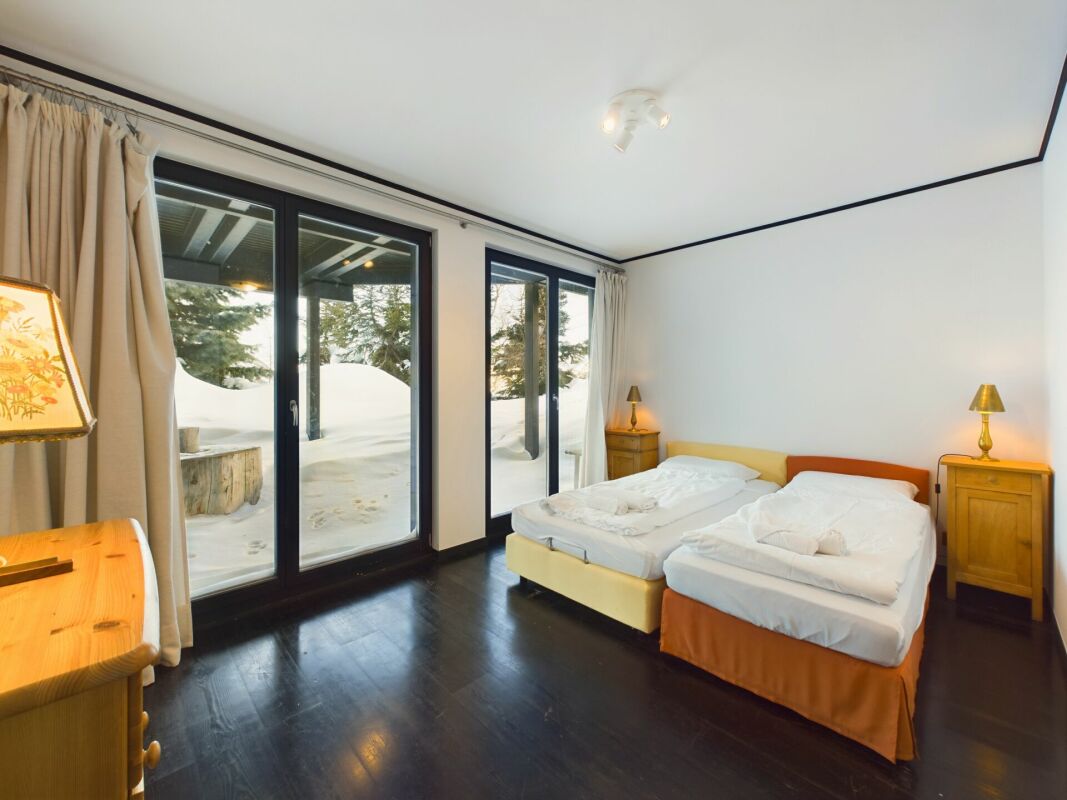 Schlafzimmer mit großen Fenstern zum verschneiten Außenbereich