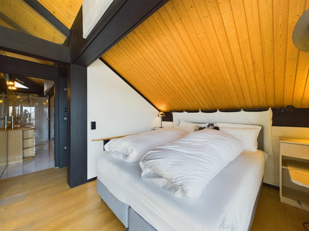 Dachgeschoss-Schlafzimmer mit sichtbaren Holzbalken