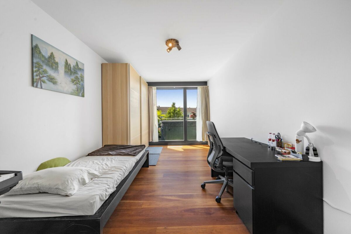 Schlichtes Schlafzimmer mit Arbeitsbereich und Balkonzugang