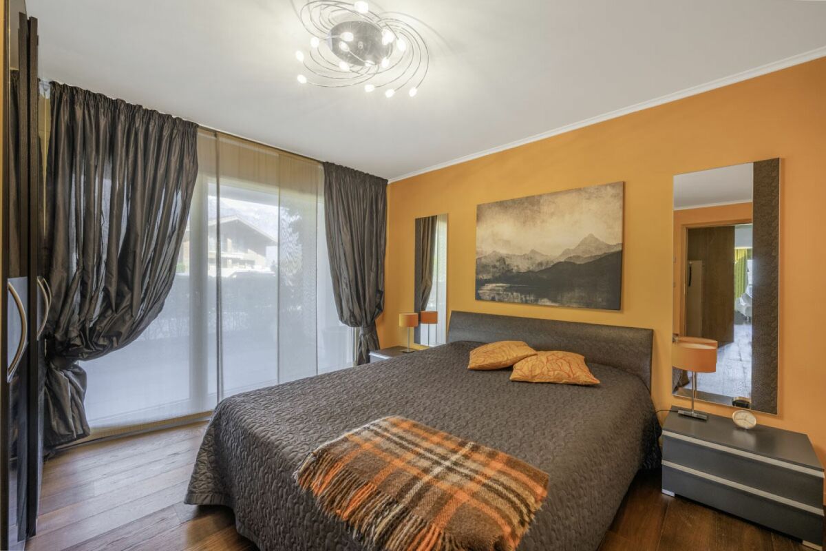 Modernes Schlafzimmer mit dunkler Bettwäsche und großer Fensterfront