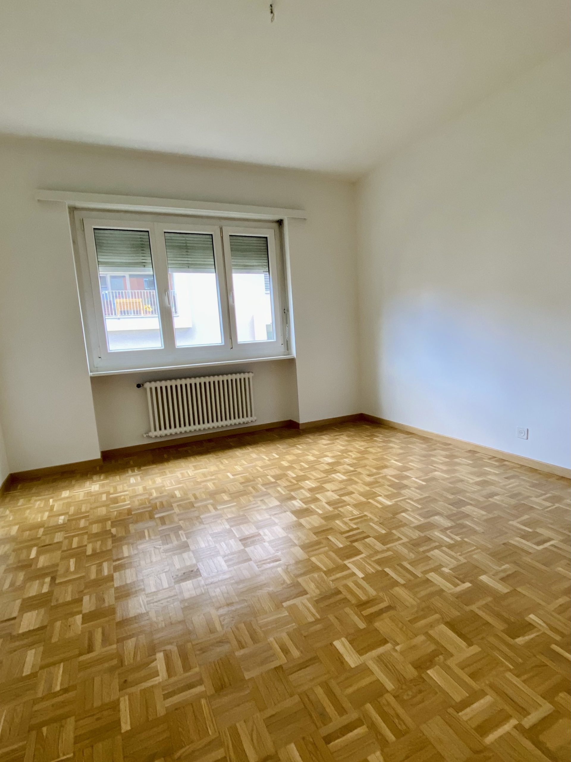 Leerer Wohnraum mit Parkett und Fenster