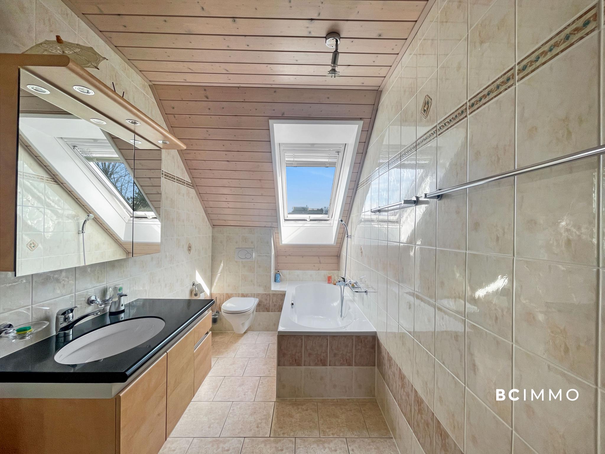 Helles Dachgeschoss-Badezimmer mit Badewanne und Dachfenstern