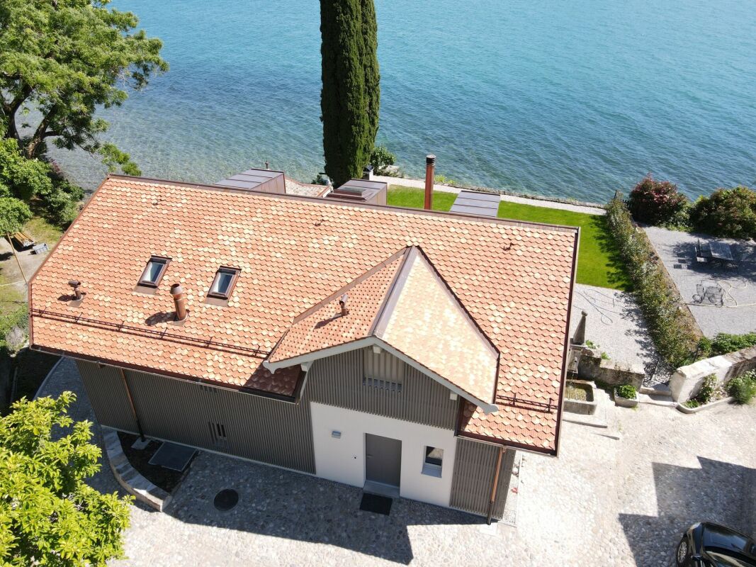 Seeblick von oben auf ein Haus mit Ziegeldach