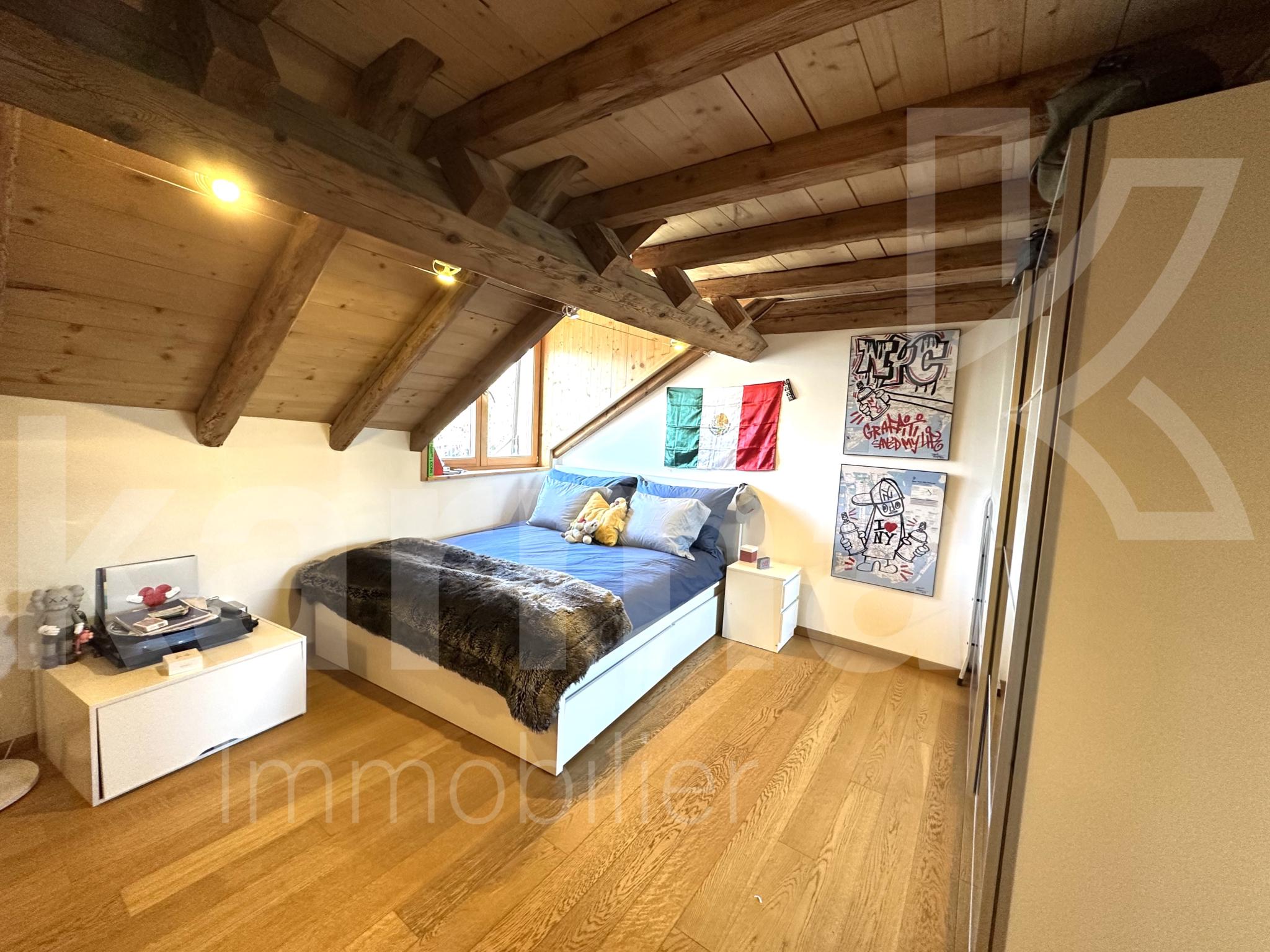 Dachgeschoss-Schlafzimmer mit sichtbaren Holzbalken