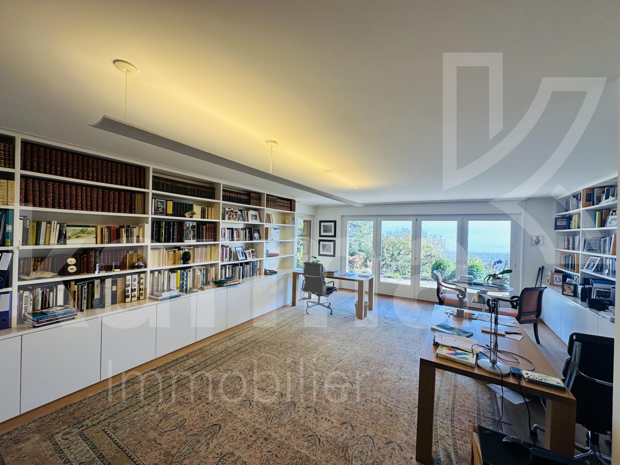 Großzügiges, helles Arbeitszimmer mit Bibliothekswänden und Blick ins Grüne