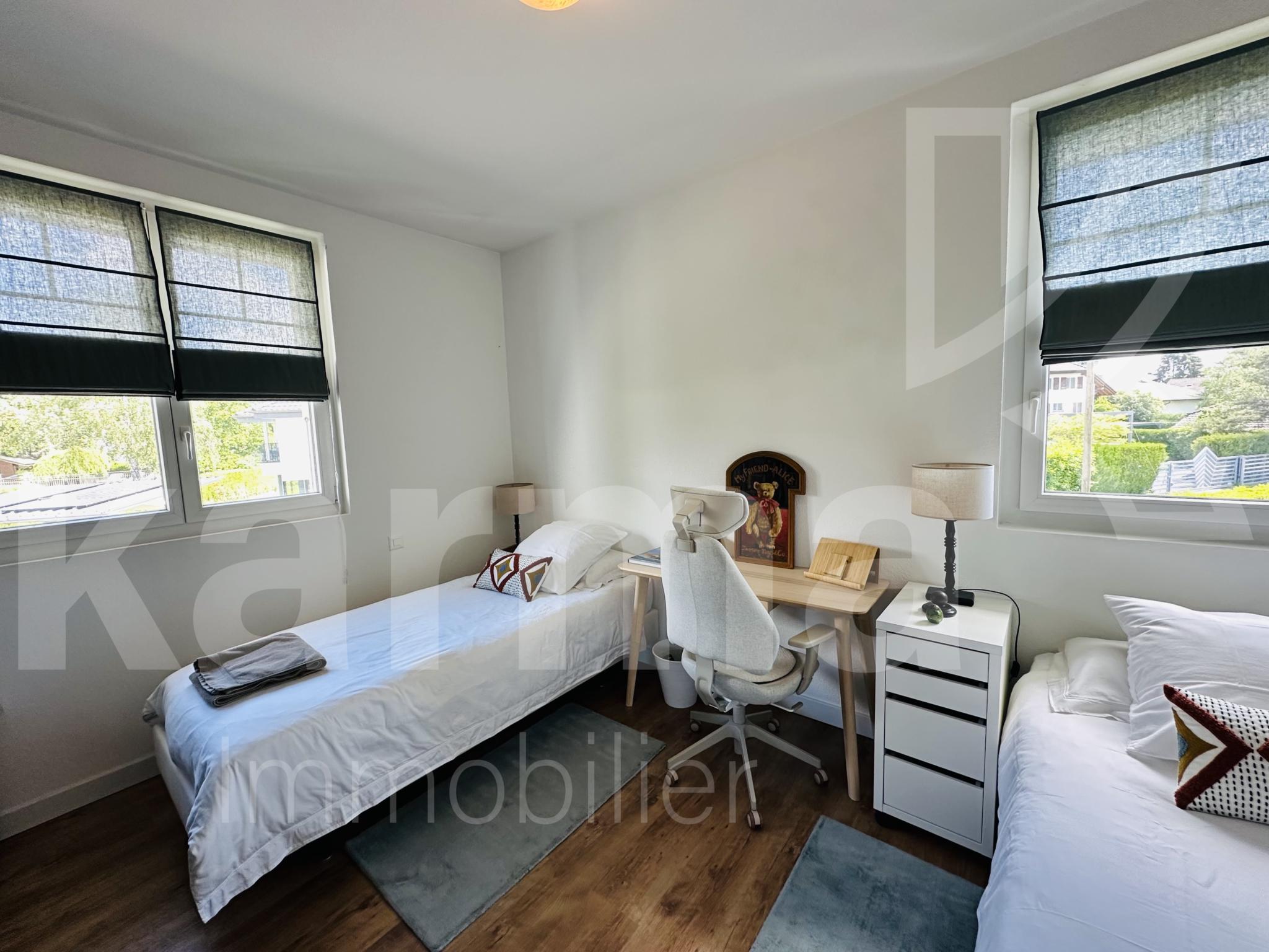 Helles Schlafzimmer mit zwei Betten und Arbeitsbereich