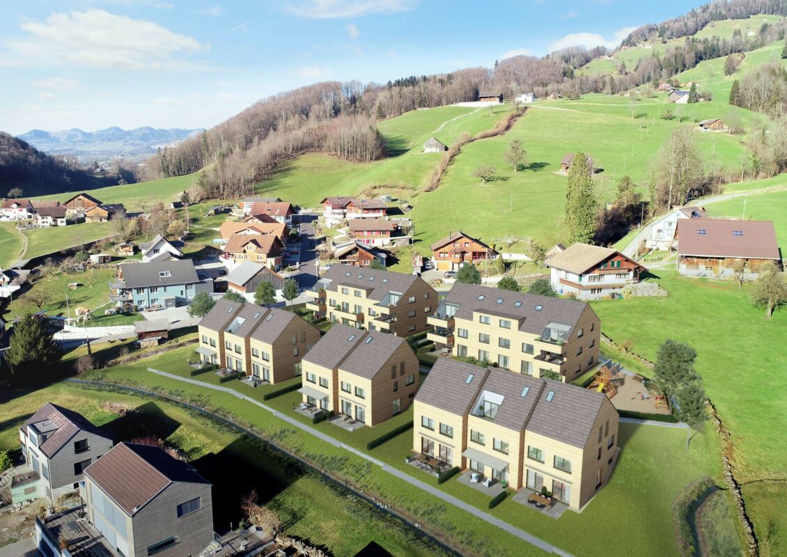 Luftaufnahme eines Wohngebiets in alpiner Hügellandschaft