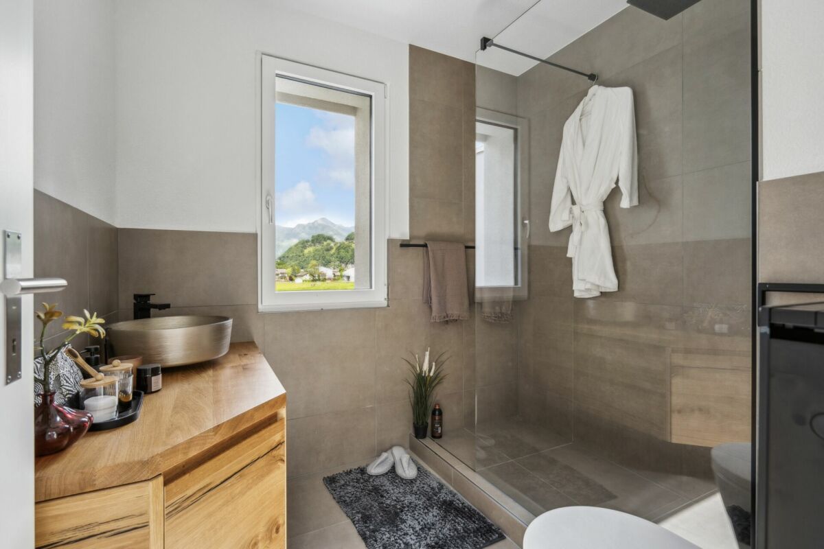 Modernes Badezimmer mit Naturtönen und Blick ins Grüne