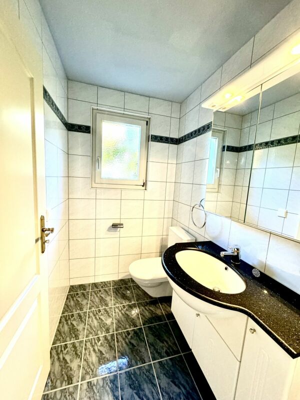 Kleines, helles Badezimmer mit Wandfliesen und schwarzer Waschtischplatte
