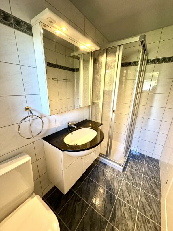 Kleines Badezimmer mit Dusche und Waschtisch