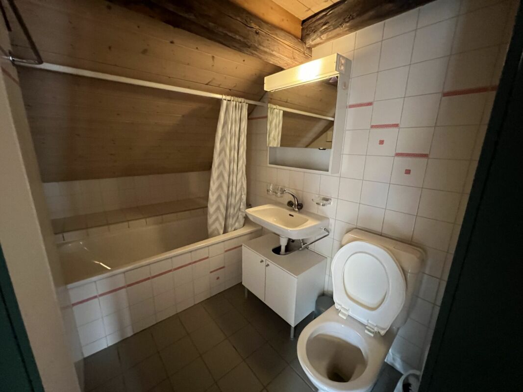 Badezimmer mit Badewanne und WC unter Dachschräge