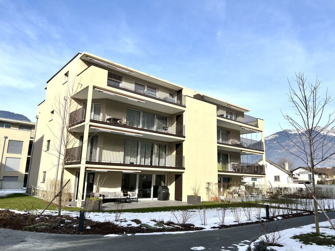 Mehrfamilienhaus mit Balkonen und Bergkulisse