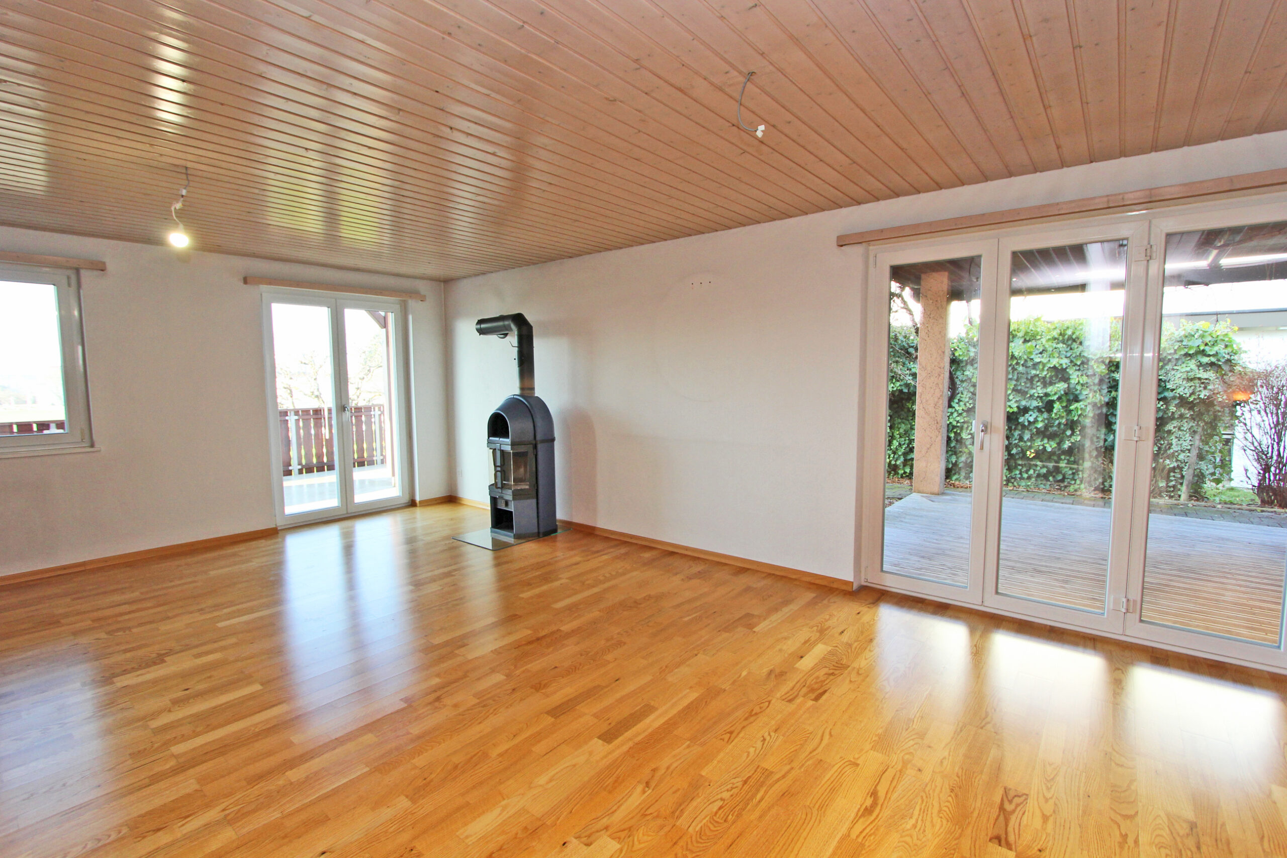 Leeres Wohnzimmer mit Kaminofen und Terrassentüren