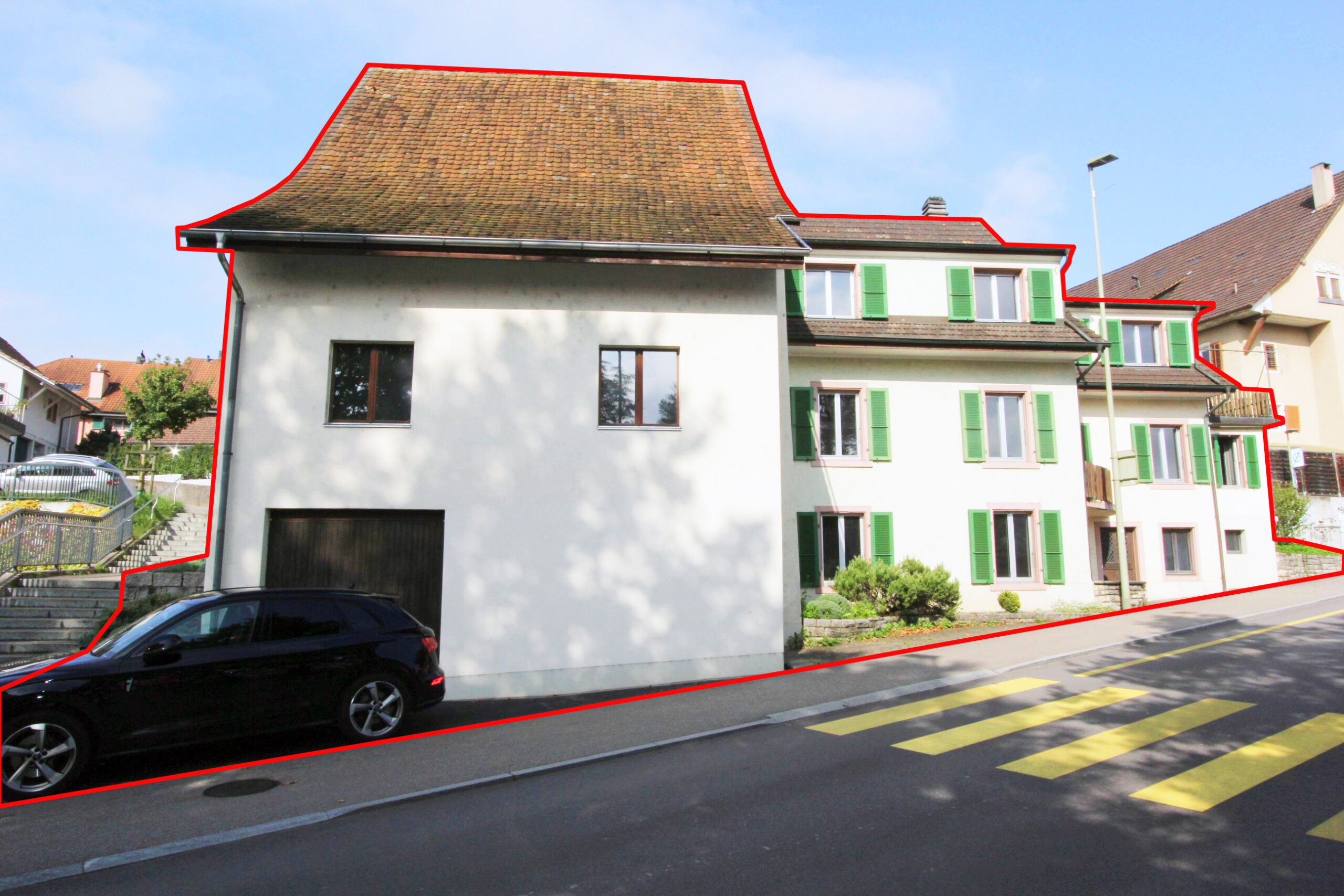 Straßenansicht eines Wohnhauses mit Satteldach und grünen Fensterläden