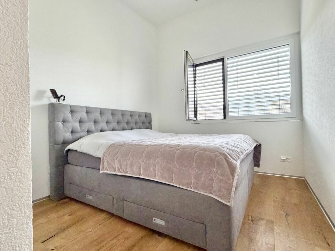 Helles Schlafzimmer mit grauem Polsterbett