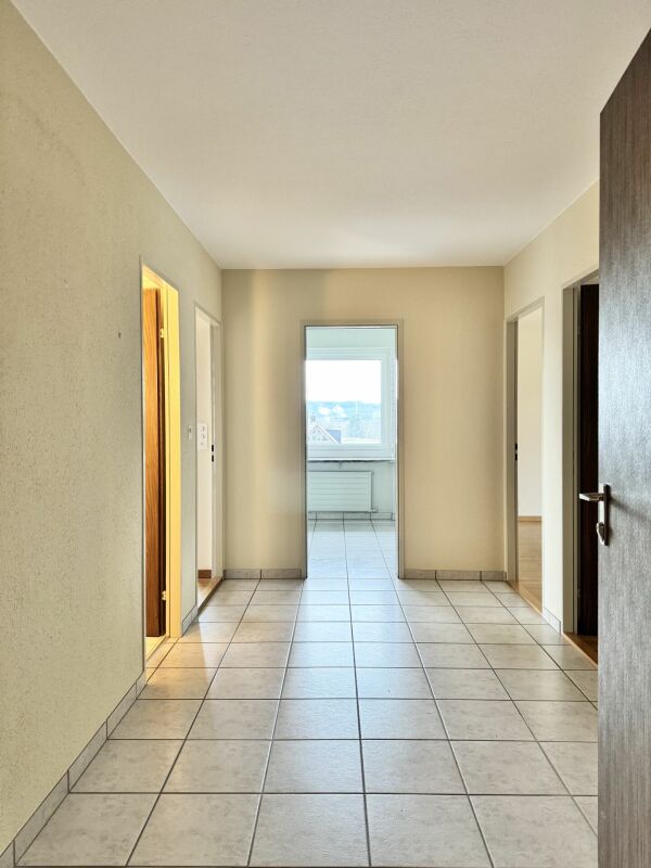 Flur mit Fliesenboden und Blick ins helle Zimmer