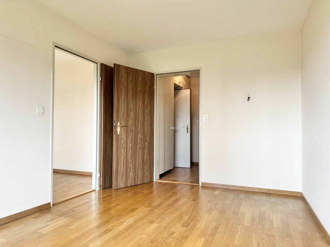 Heller, leerer Raum mit Holzboden und zwei Türen