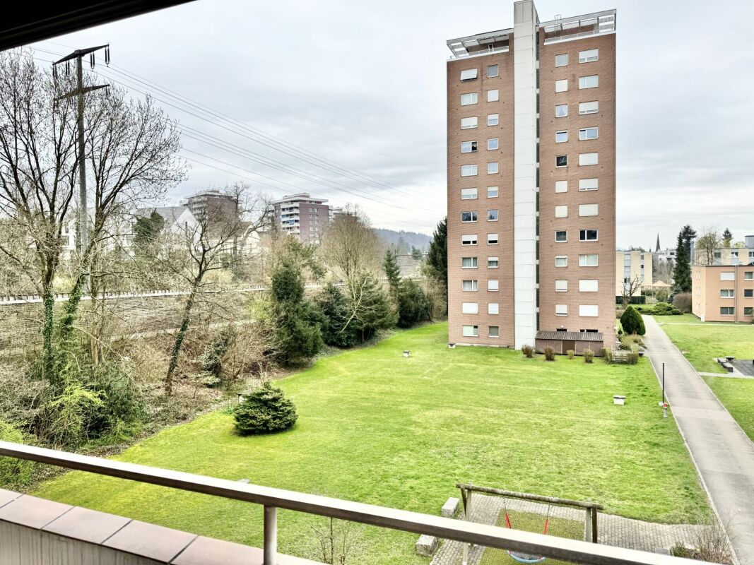 Blick von einem Balkon auf eine Wohnanlage und Grünfläche