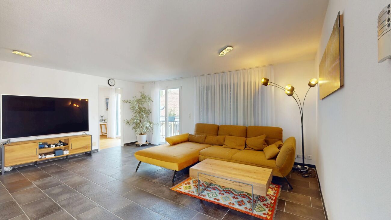 Helles Wohnzimmer mit L-förmigem Sofa und TV