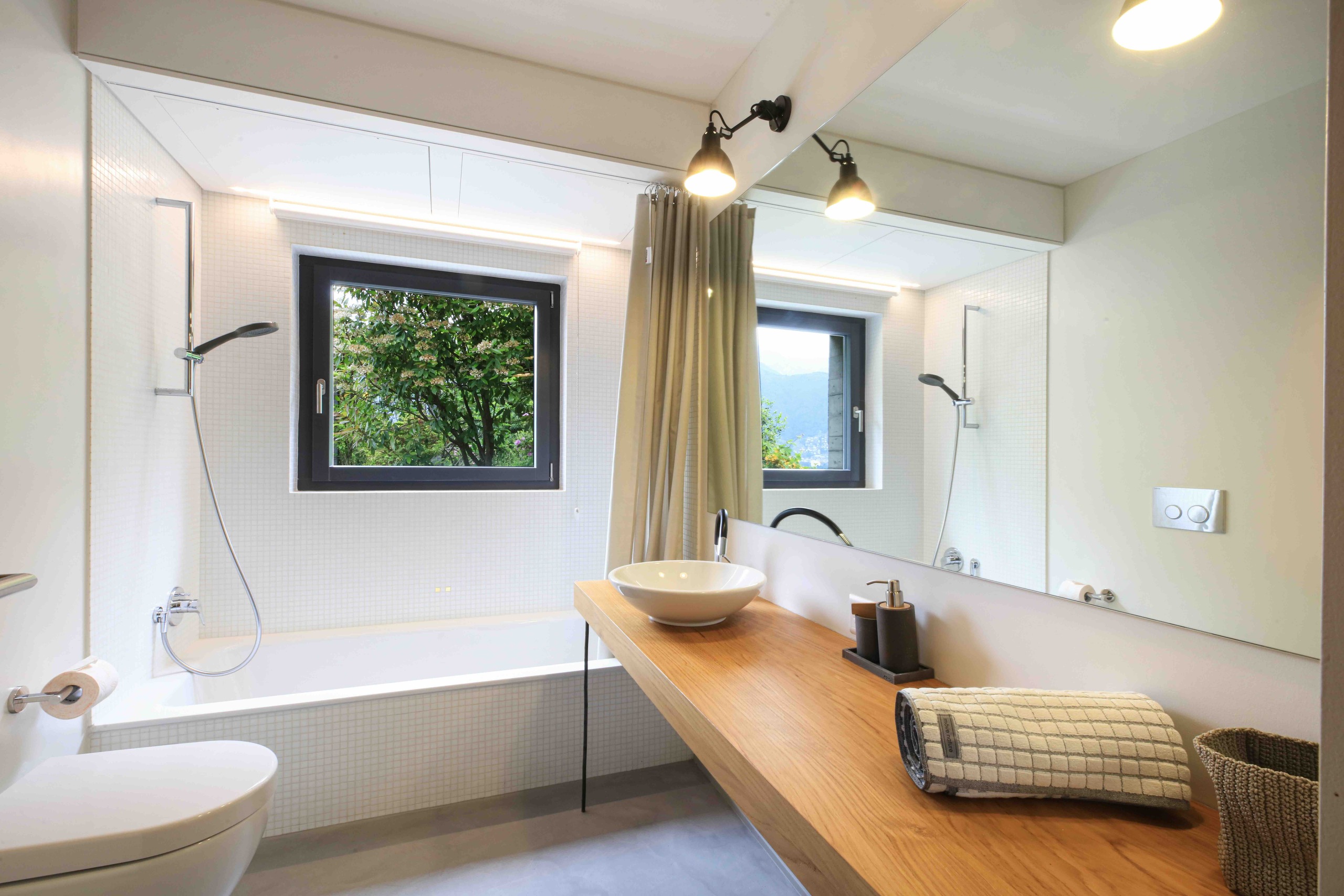 Helles modernes Badezimmer mit Wannenbereich und Holzablage