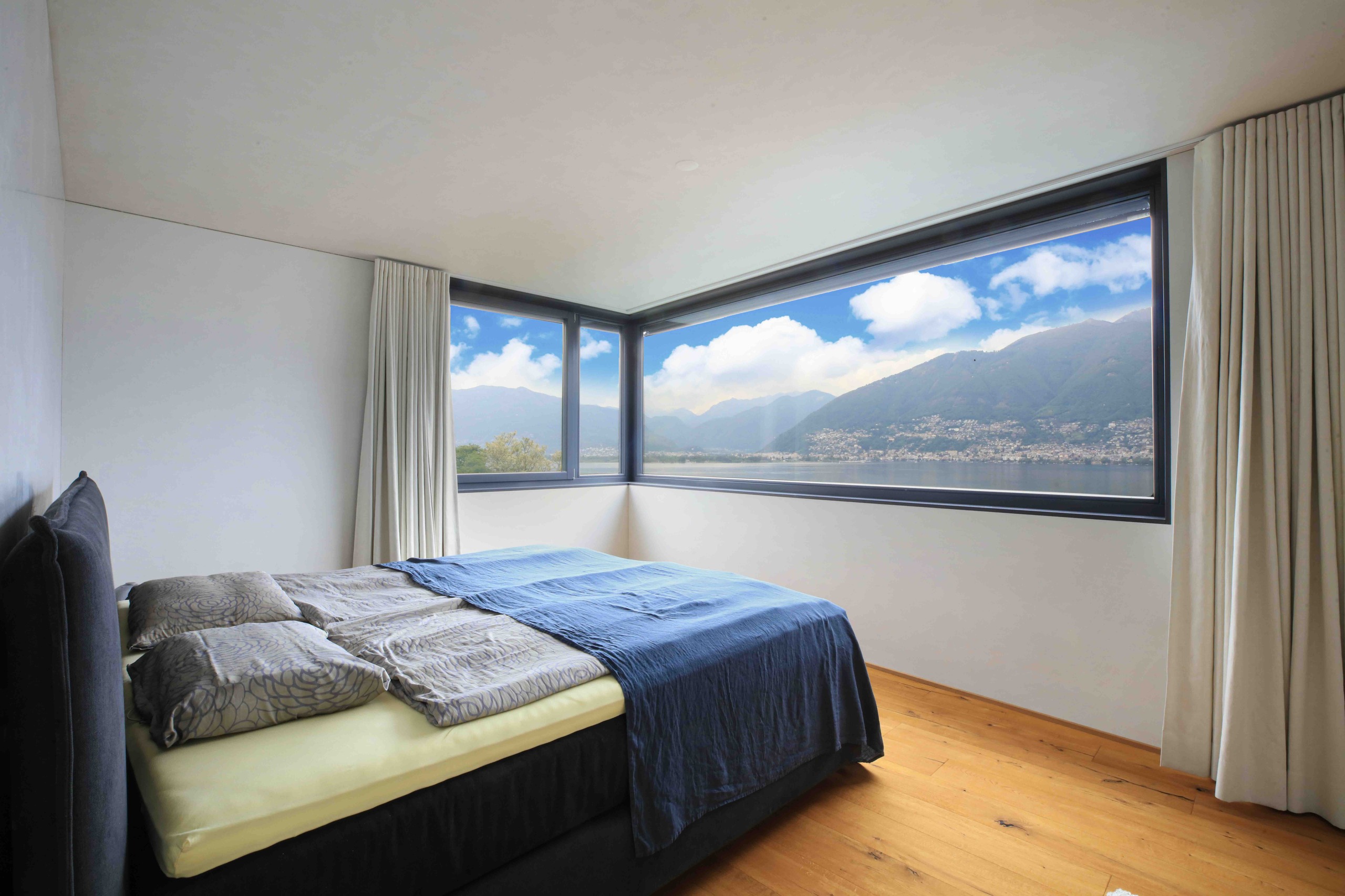 Schlafzimmer mit Panoramafenster und Seeblick