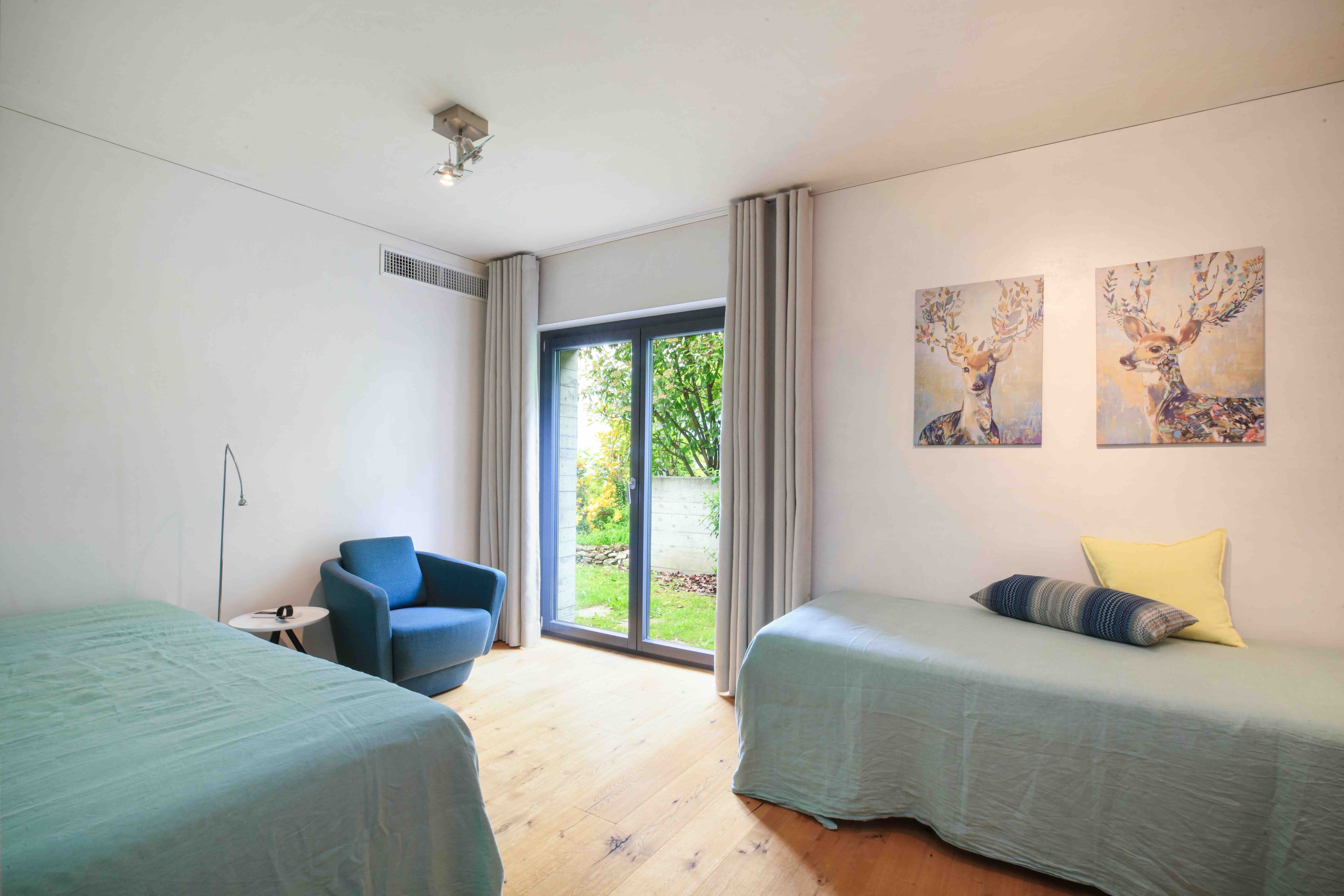Helles Schlafzimmer mit zwei Betten und Gartenzugang