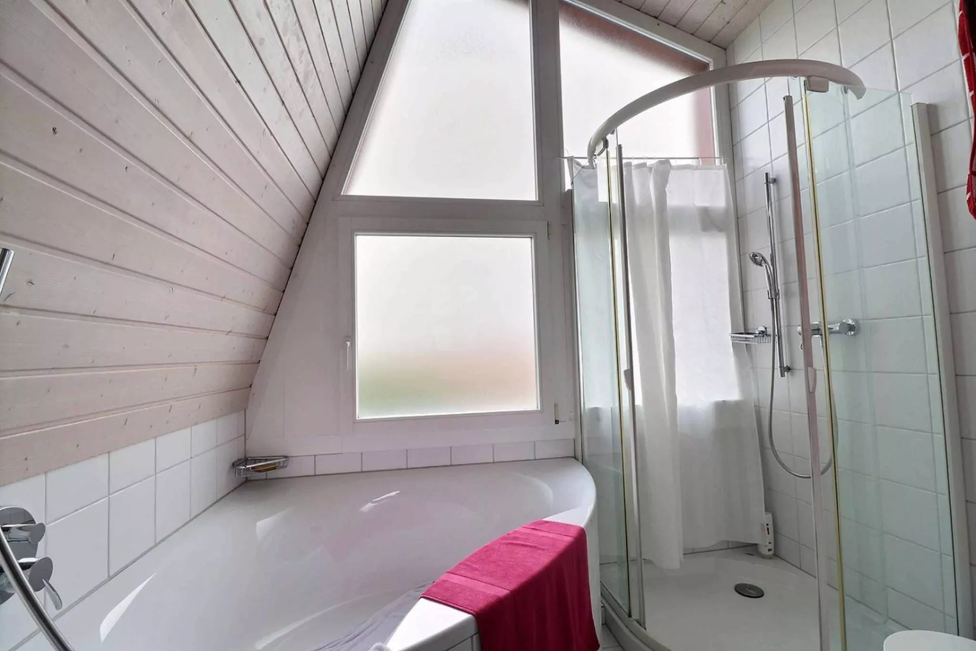 Badezimmer mit Badewanne und Glasdusche unter Dachschräge