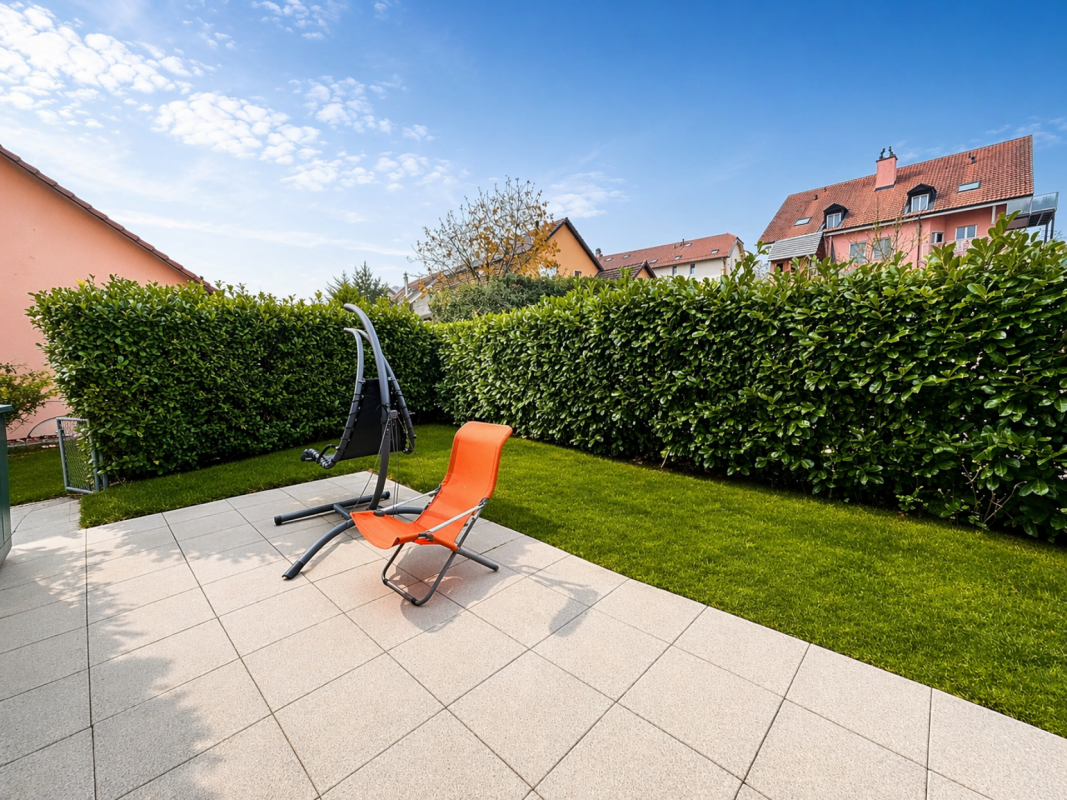 Gepflegte Terrasse mit Garten und Liegestuhl
