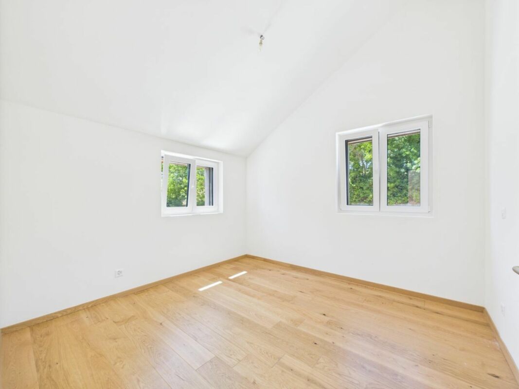 Heller leerer Raum mit Holzboden und weißen Wänden