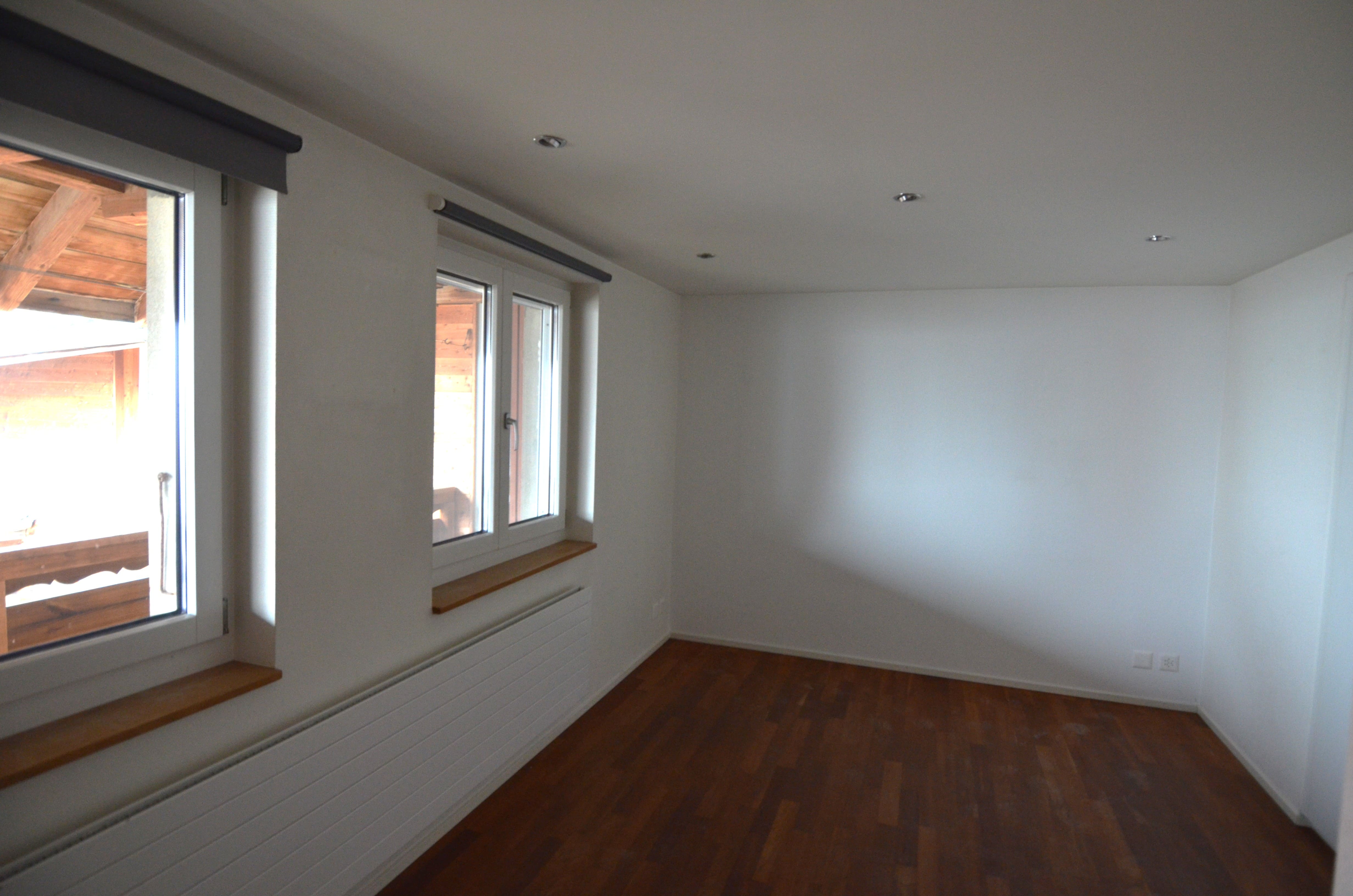 Leerer Raum mit Holzfußboden und Fenstern