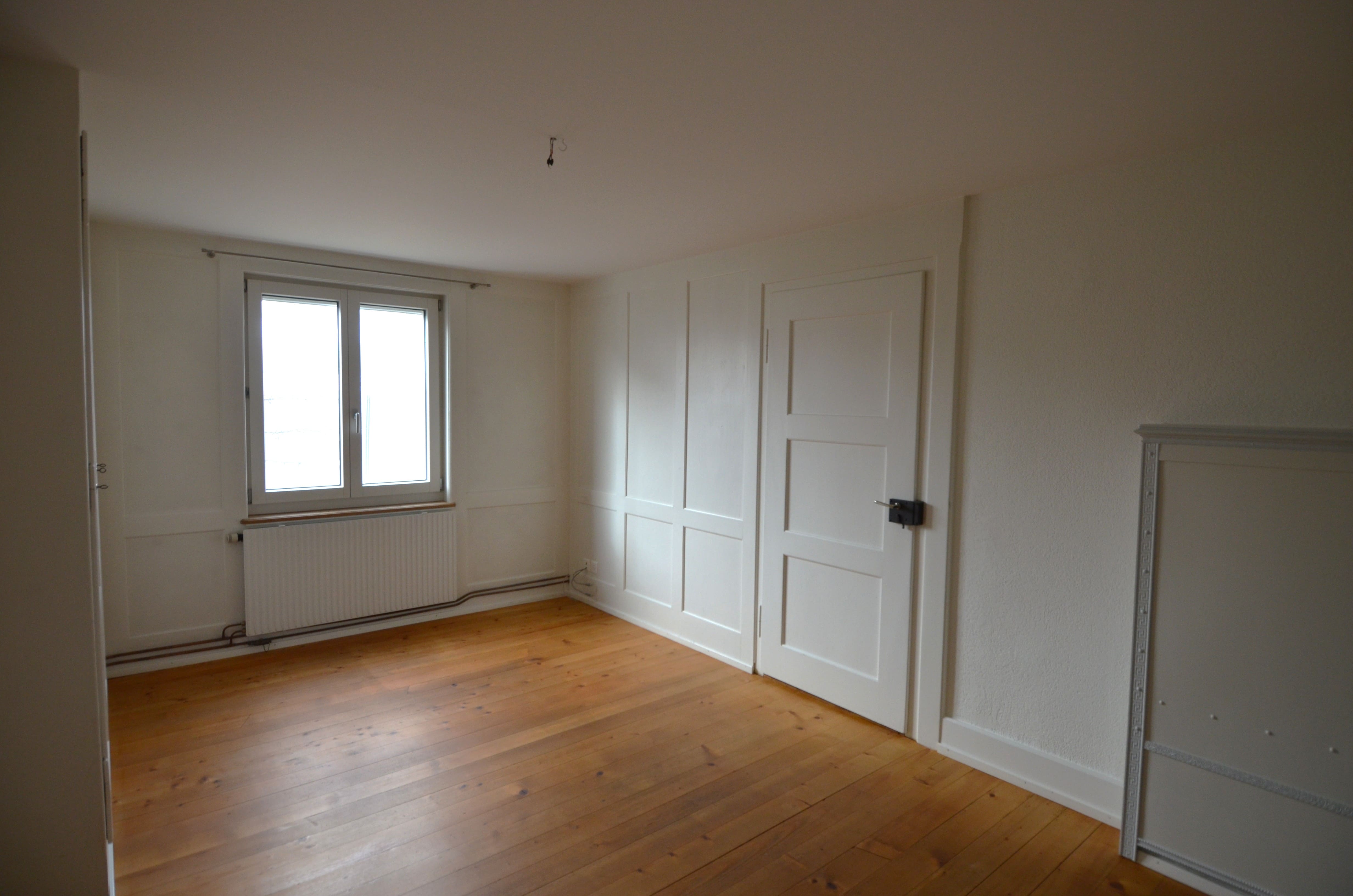 Helles, leeres Schlafzimmer mit Holzboden