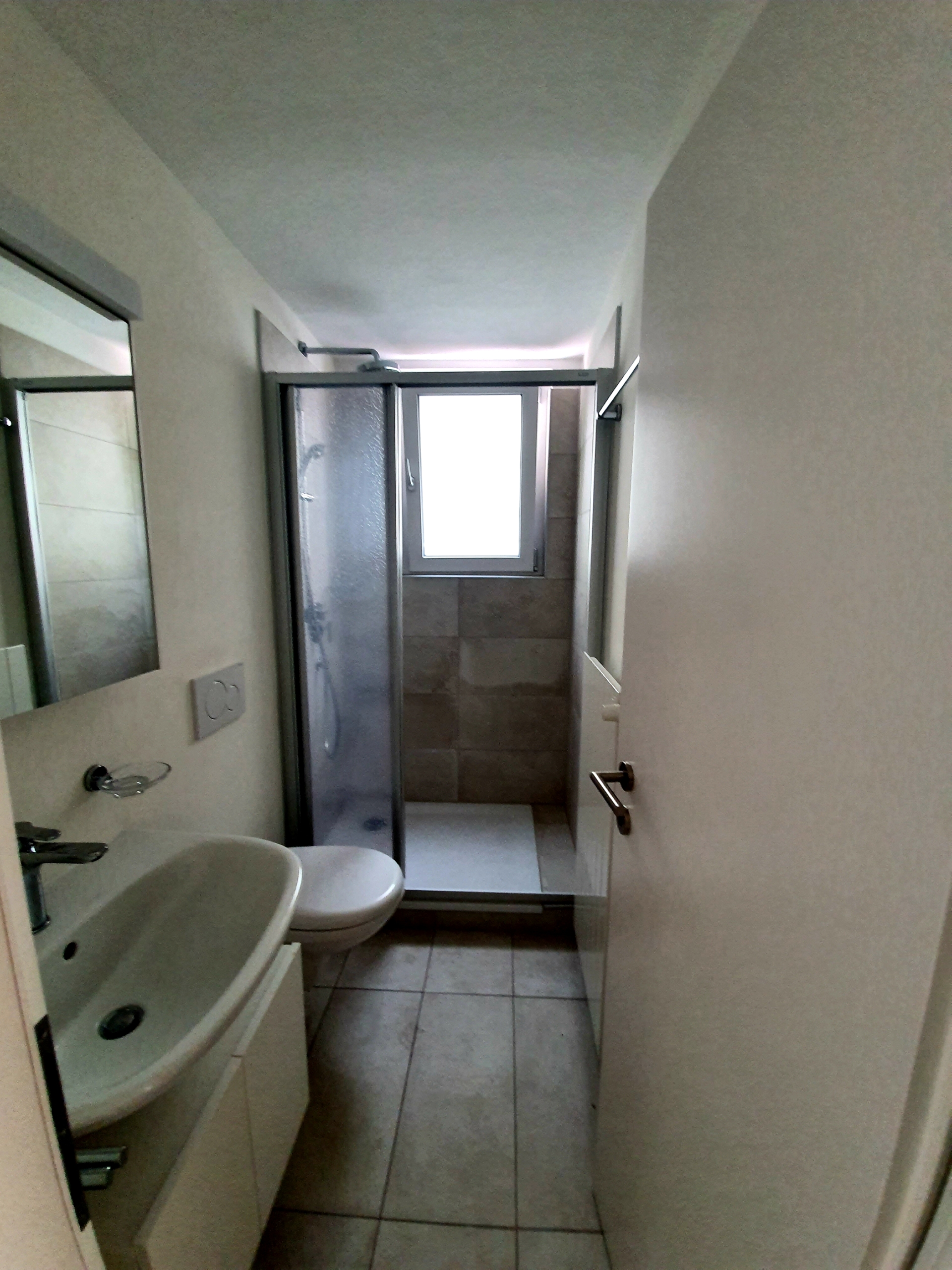 Schmales Badezimmer mit Dusche und Waschbecken