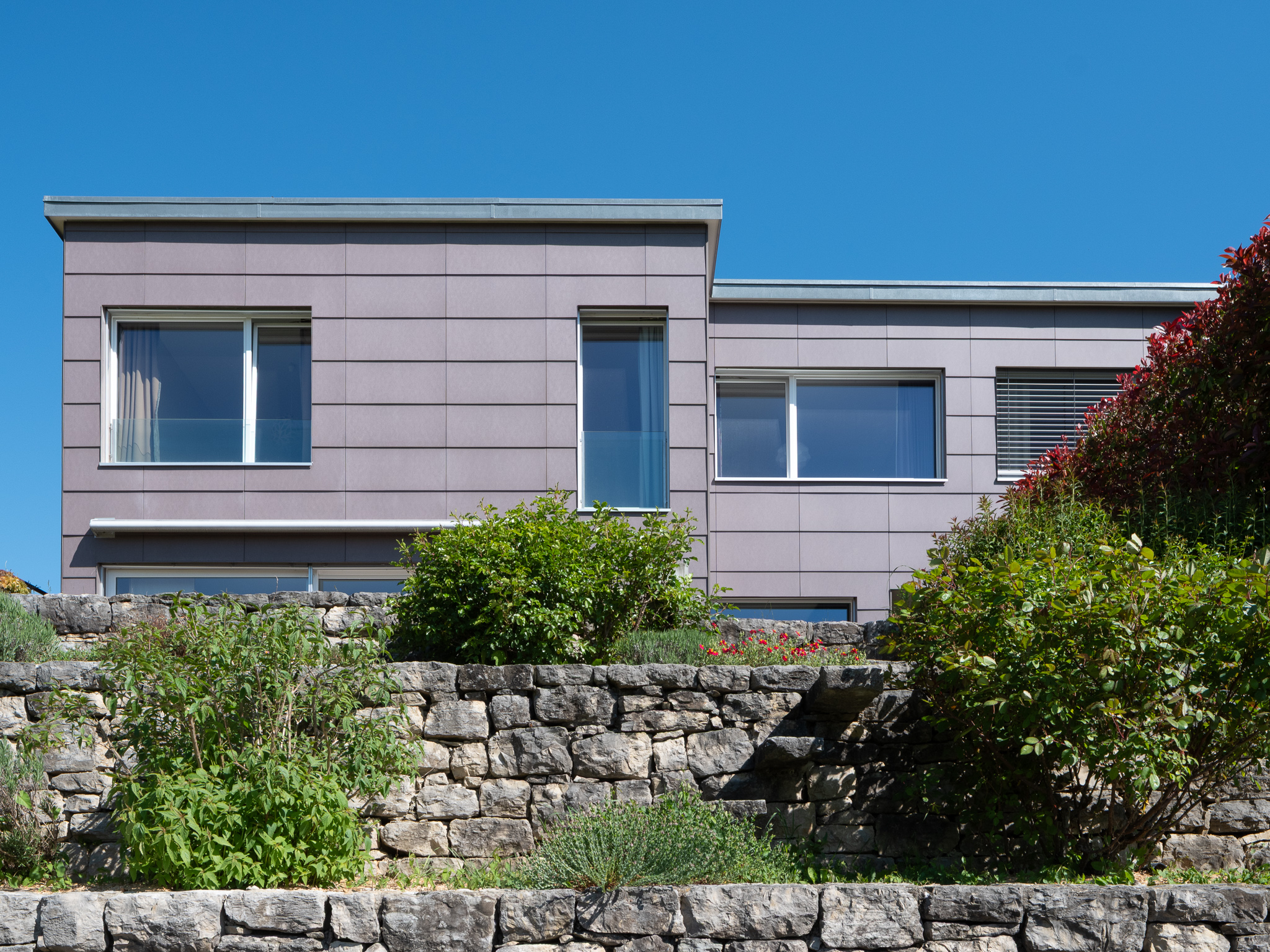Moderne Außenansicht mit gestaffelter Fassade und Gartenmauer