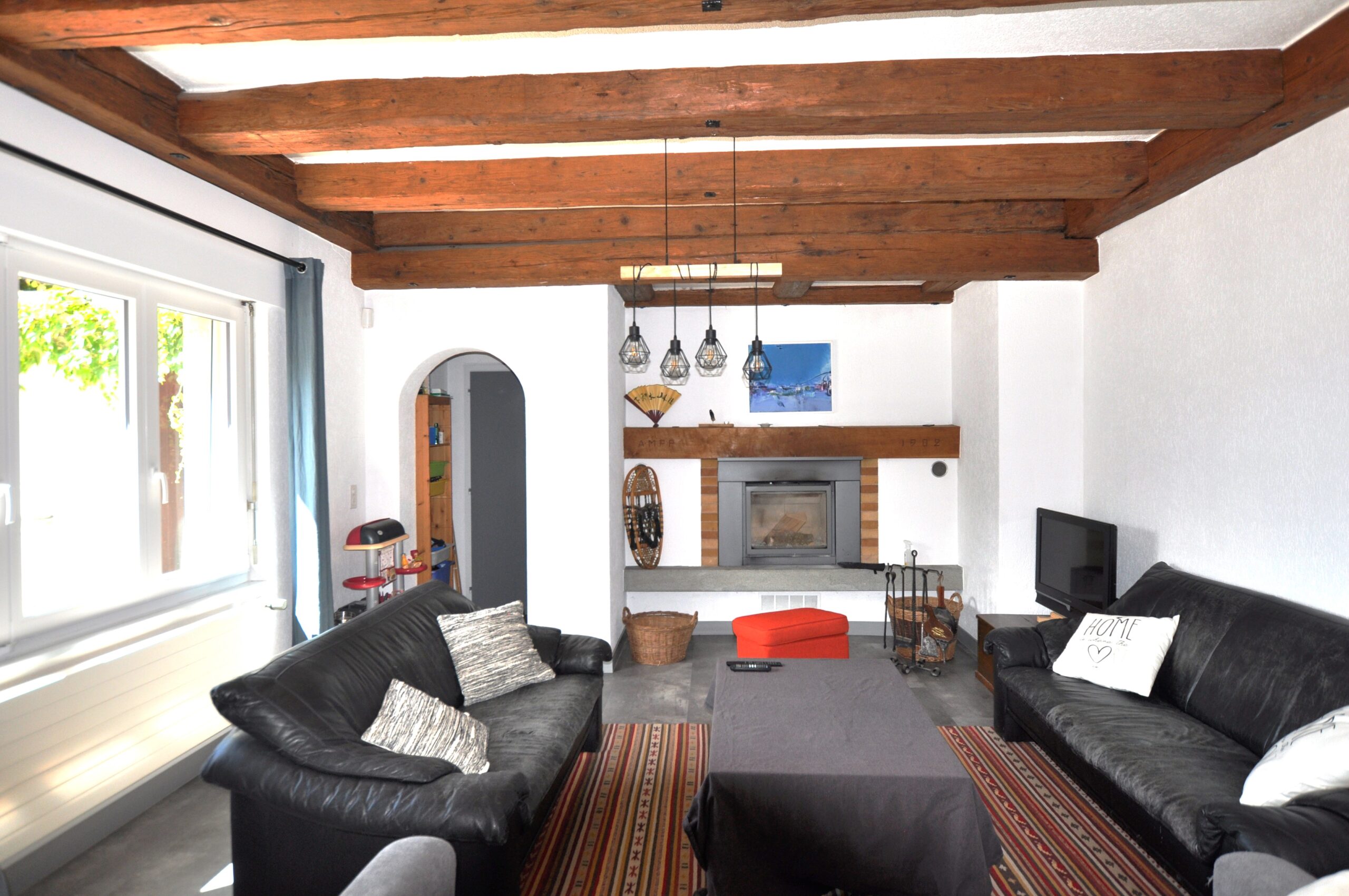 Wohnzimmer mit Kamin und sichtbaren Holzbalken