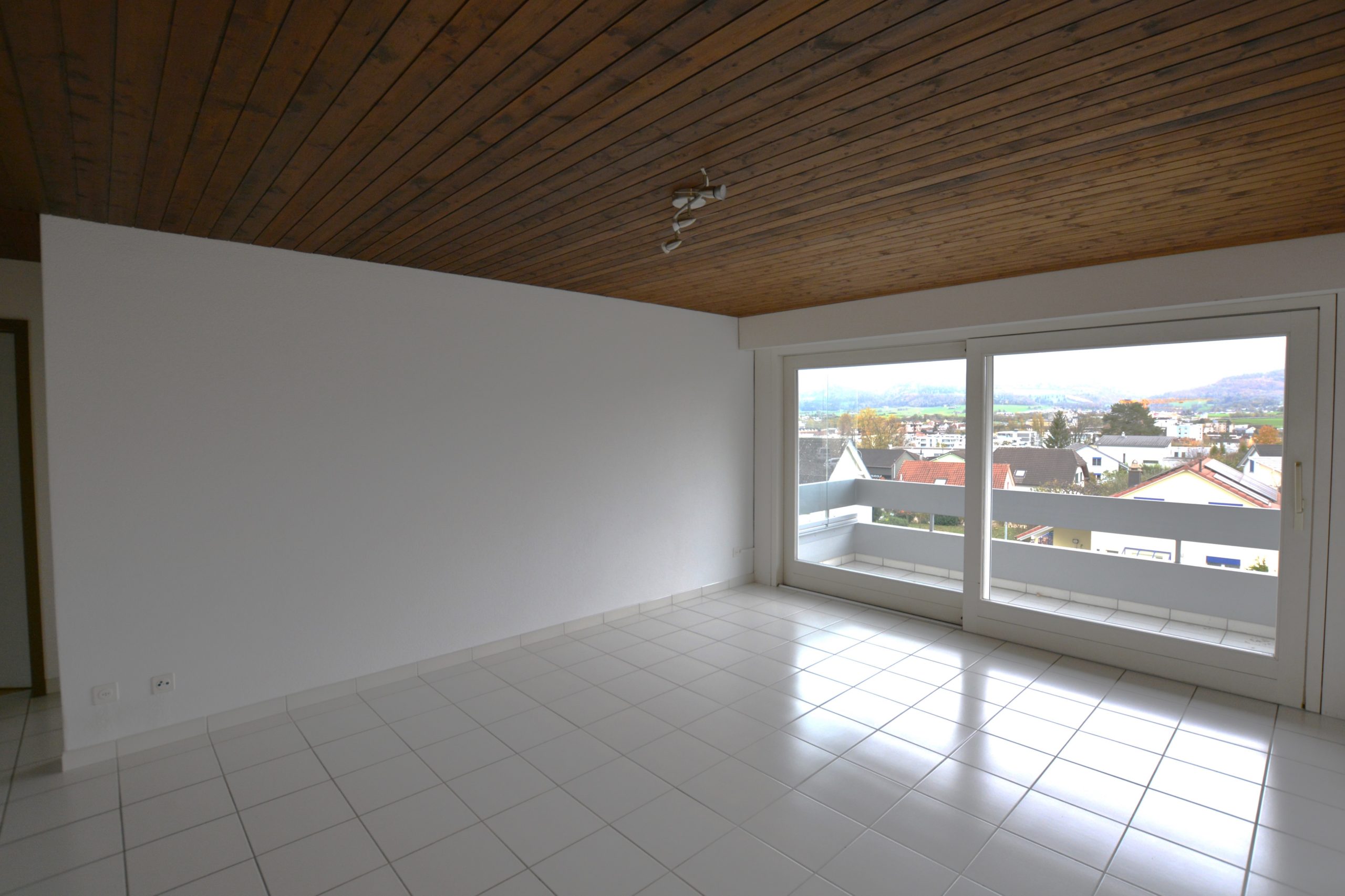 Leerer Wohnraum mit Balkon und Aussicht