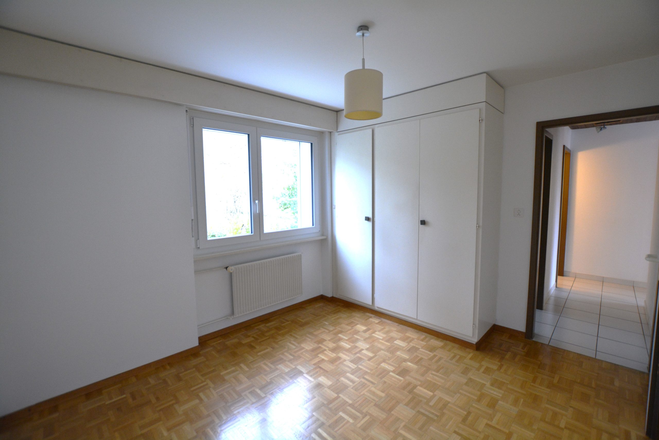 Leeres Schlafzimmer mit Parkettboden und Einbauschrank